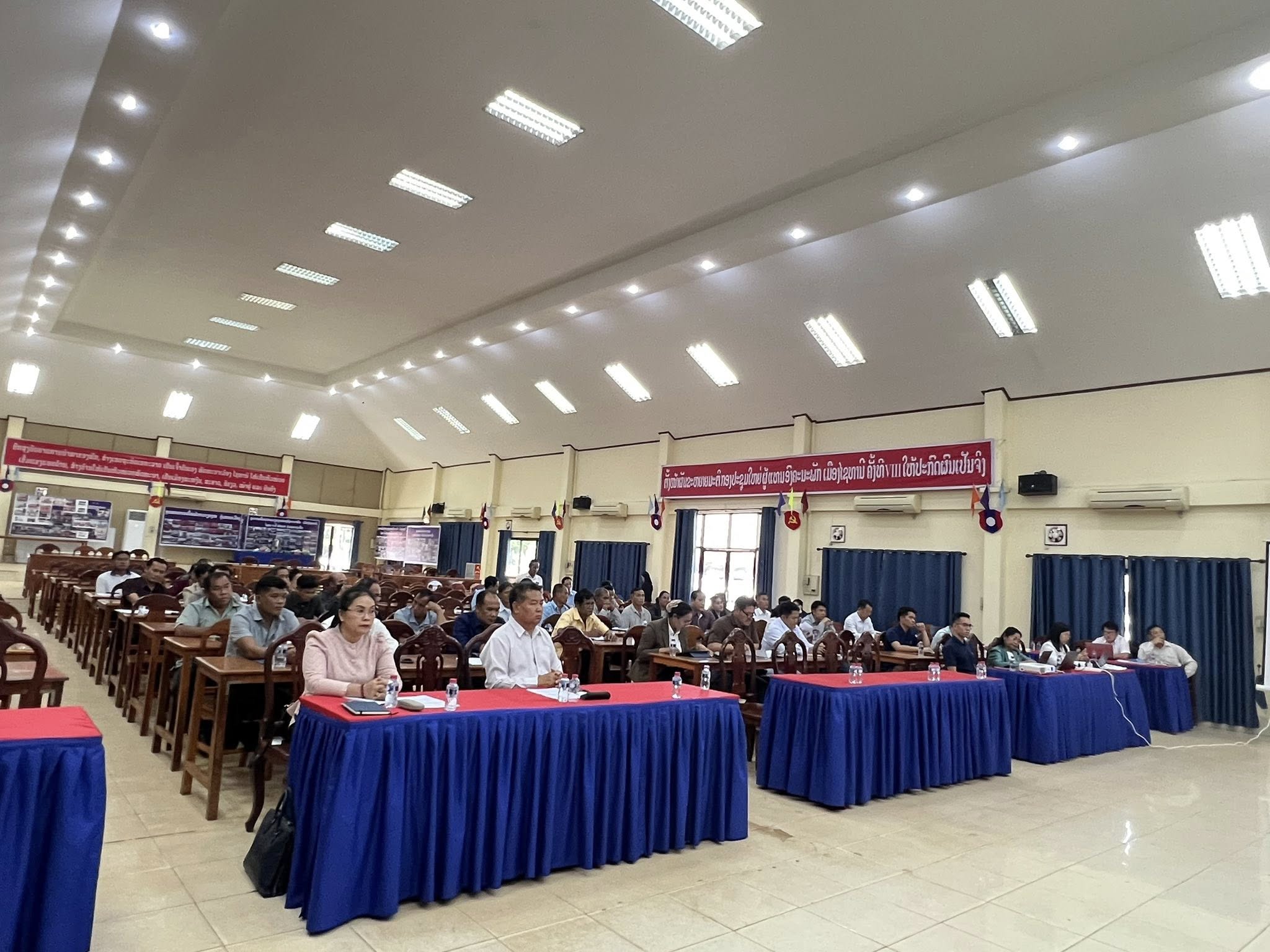 Formal consultation meeting — large hall with government officials and community representatives